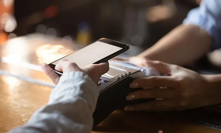 Close up view of a paying at a merchant by using mobile phone.