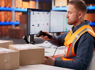 Person scanning packages with handheld barcode scanner in warehouse
