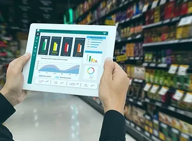 Hands holding tablet with retail analytics in supermarket aisle