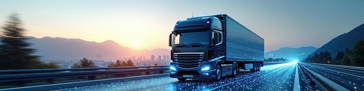 A semi truck travels down a highway, silhouetted against a vibrant sunset sky.