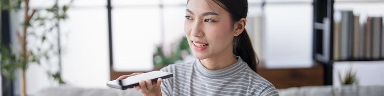 A lady holding a phone near her face and talking on speakerphone