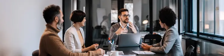 Several colleagues seated at a conference table, collaborating in a bright office environment.
