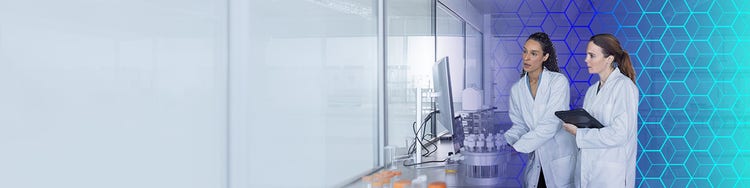 Life sciences researchers analyzing laboratory data with AI-enabled technology in a modern pharmaceutical research lab.