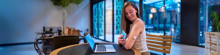A woman scanning health and fitness device through her mobile attached to her hand