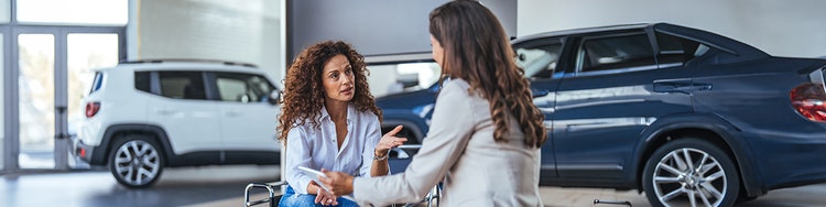 Two people discussing car options inside a modern vehicle showroom.