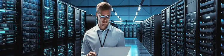 A worker looking into a laptop inside a server room