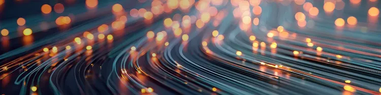 Abstract blurred fiber-optic light streaks in teal and amber, representing telecom data flow.