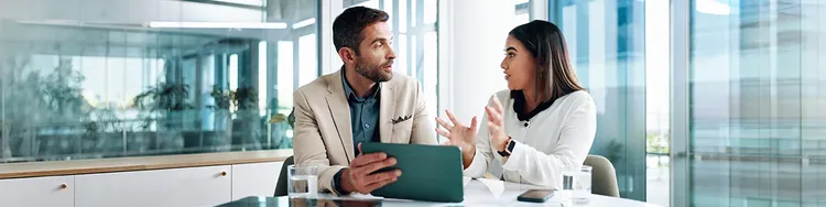 A man and woman working together on a computer, concentrating on their project in an office environment.