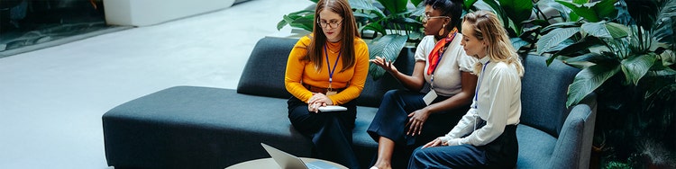 Three women are sitting in a sofa and discussing