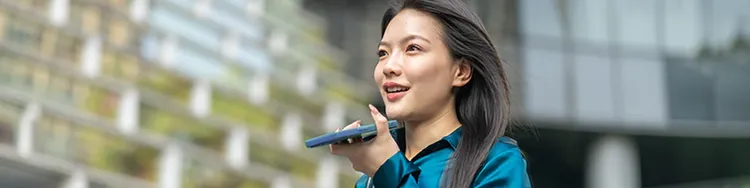 A woman holding a mobile phone close to her mouth and speaking into it