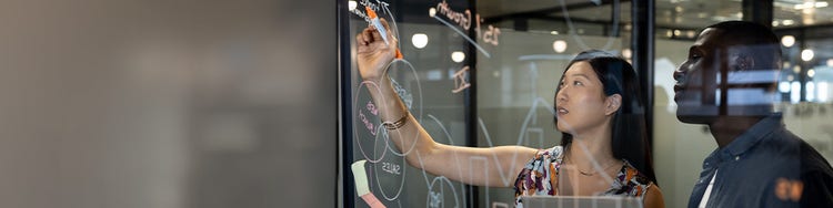 A person writing on a glass board