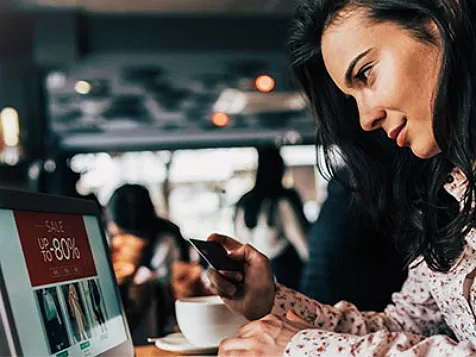 A woman holding a credit card while doing online shopping on her laptop
