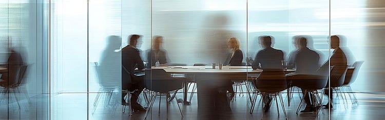 A blurred image of a glass wall behind which office professionals dressed in formals are having a board meeting
