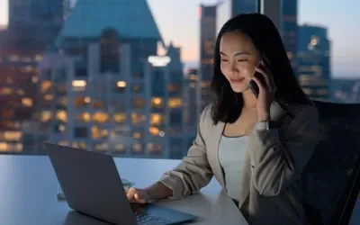 A woman on the phone while checking laptop