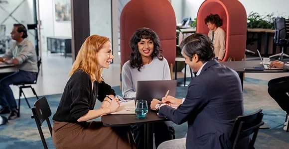 Two women and a man sitting around a table and talking