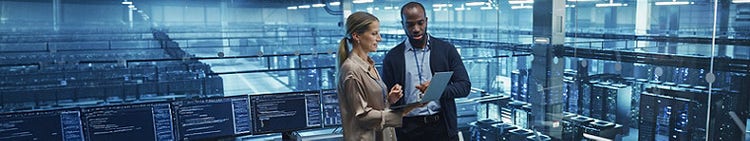 Two individuals standing in front of a server room, surrounded by rows of servers and blinking lights.