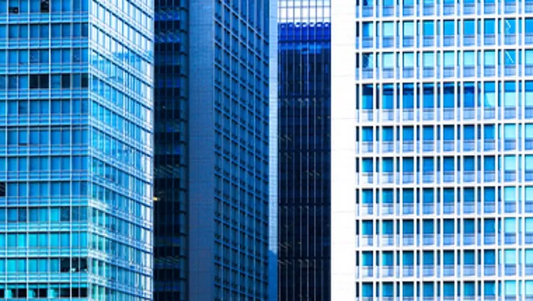Modern corporate skyscrapers with blue glass facades, representing business, finance, commercial real estate, and urban growth.