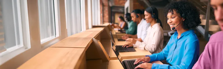 A row of colleagues on their headphones and working on their laptop.