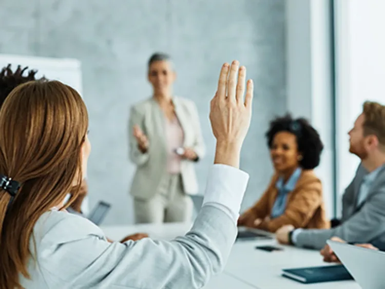 A women raise his hand in a business meeting