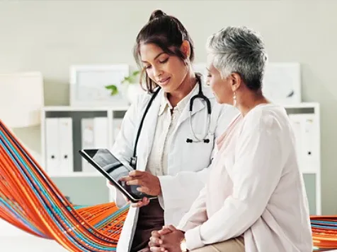 Doctor showing information on a tablet to an older patient