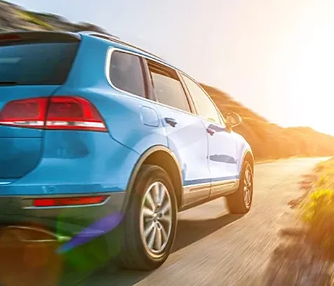 A car driving on a hill towards uphill where the sun is shining