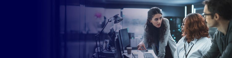 Colleagues collaborating monitors as woman points, discussing work in office